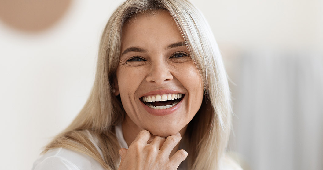 Portrait of laughing beautiful woman touching her face<br />
